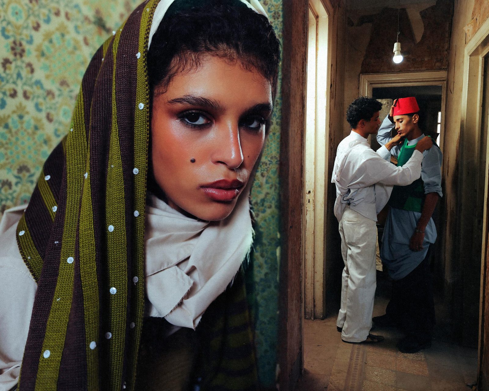 Split scene: a veiled model in close-up beside a hallway where a man in a red fez is being dressed