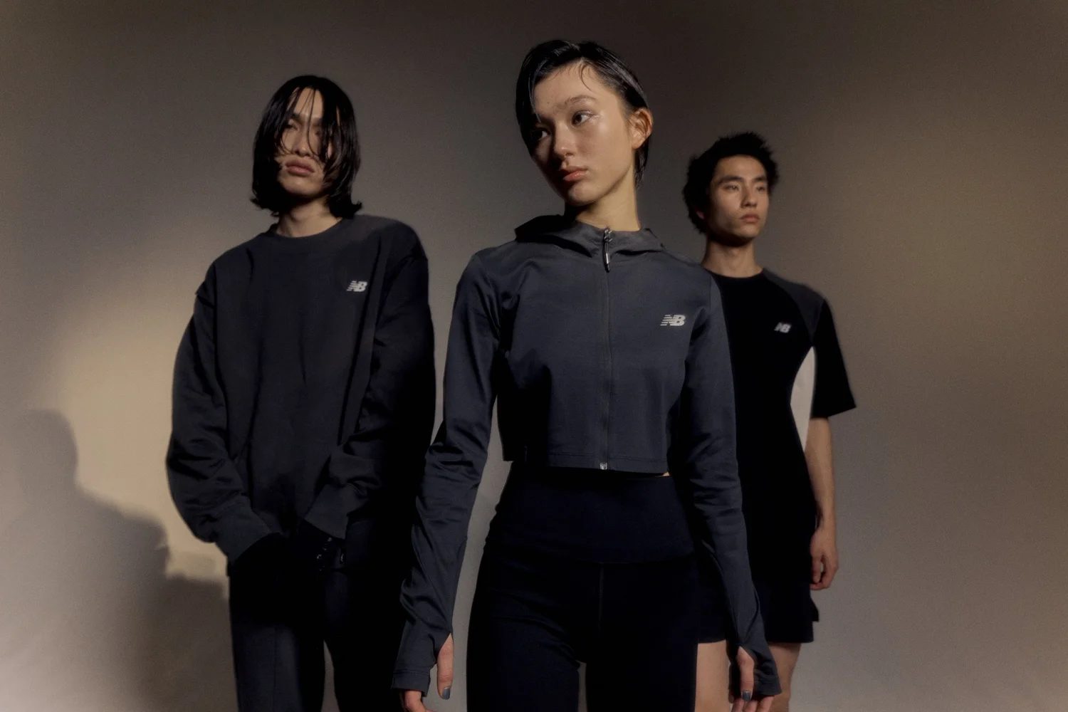 Three models in black New Balance training wear, studio group portrait